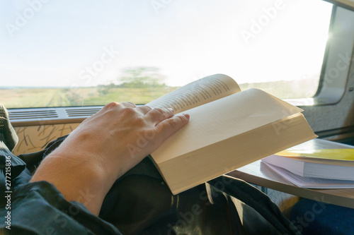 Person reading book on a train