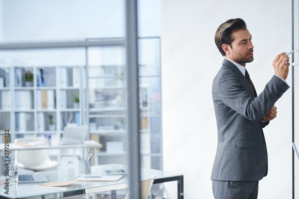 Young confident teacher in elegant suit pointing at board Young confident teacher in elegant suit pointing at board
