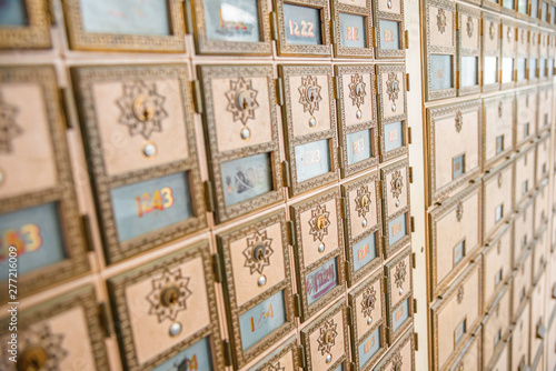 Rows of mid-century modern design post office mailboxes in brass metal.