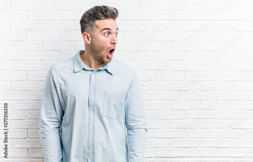 Young handsome man against a bricks wall being shocked because of something she has seen. Young handsome man against a bricks wall being shocked because of something she has seen.