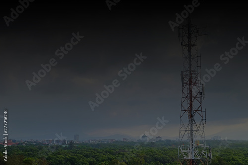 High antenna tower in rural area with dark stormy sky
