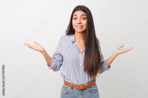 Young pretty arab woman confused and doubtful shrugging shoulders to hold a copy space.