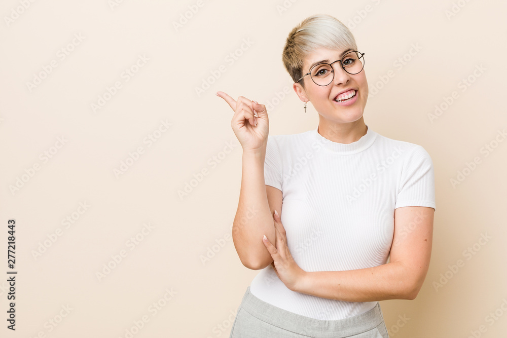 Young authentic natural woman wearing a white shirt smiling cheerfully pointing with forefinger away. Young authentic natural woman wearing a white shirt smiling cheerfully pointing with forefinger away.