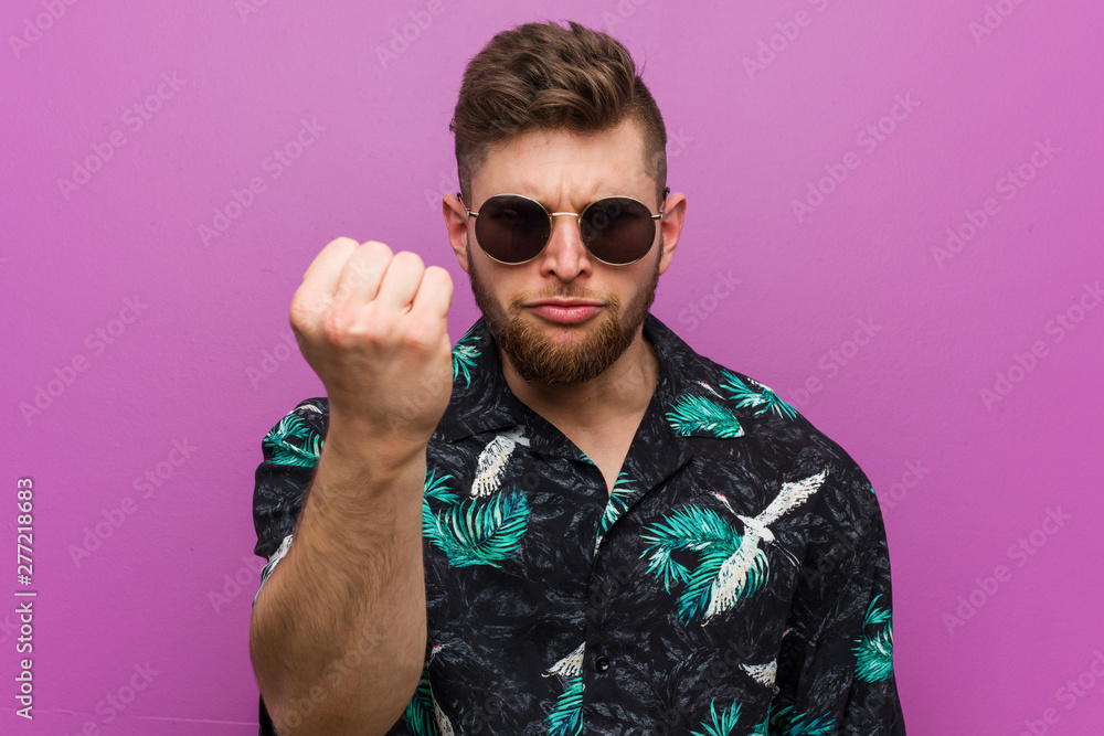 Fototapeta premium Young man wearing a vacation look showing fist to camera, aggressive facial expression.