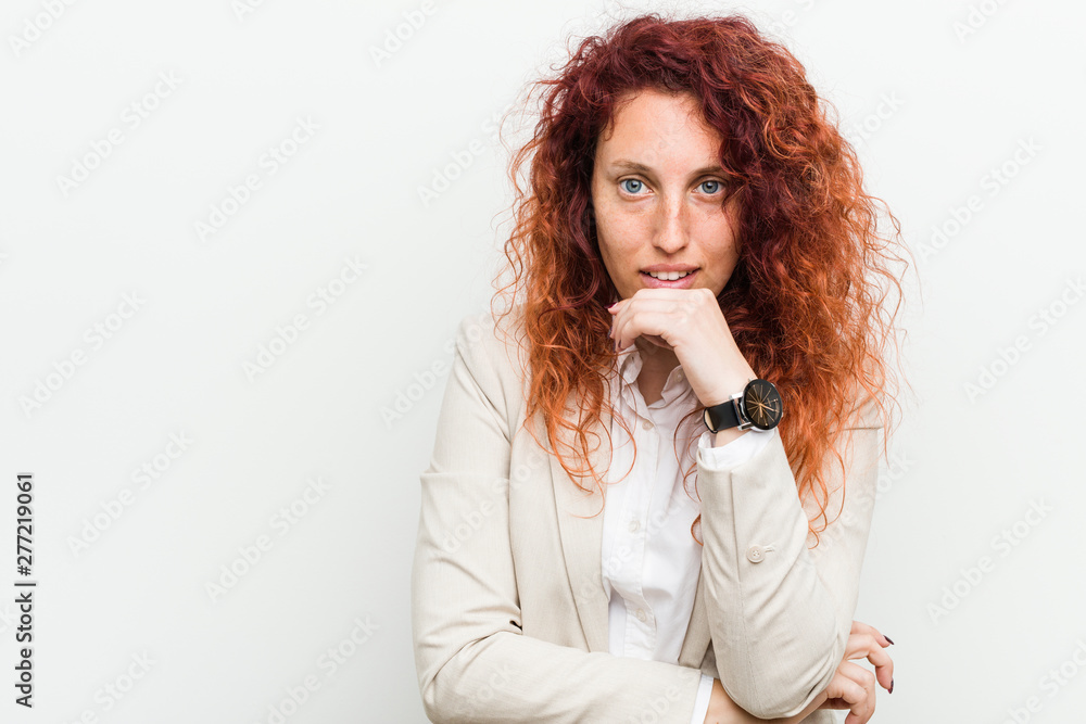 Young natural redhead business woman isolated against white background smiling happy and confident, touching chin with hand. Young natural redhead business woman isolated against white background smiling happy and confident, touching chin with hand.