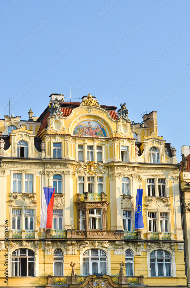 Beautiful traditional house with yellow facade located on the Old Town Square in the Czech capital Prague. Photographed in morning golden hour. Vertical picture. Old town, landmark. Tourist place