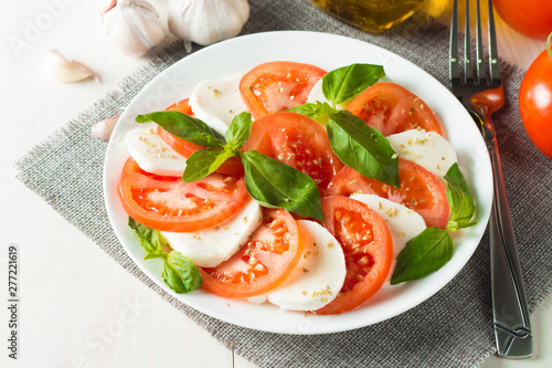 Close-up photo of caprese salad with ripe tomatoes, basil, buffalo mozzarella cheese. Italian and Mediterranean food concept. Fresh and healthy organic meal. Starter and antipasti.