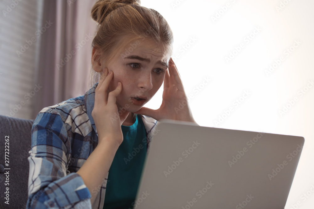 Shocked teenage girl with laptop indoors. Danger of internet Shocked teenage girl with laptop indoors. Danger of internet