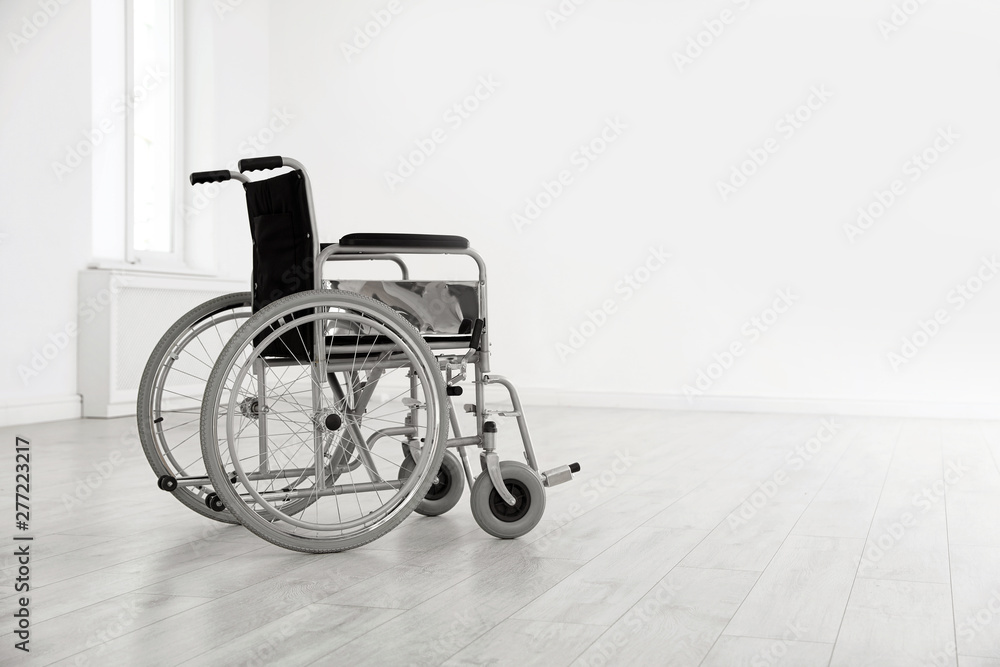 Modern wheelchair in empty room, space for text. Medical equipment Modern wheelchair in empty room, space for text. Medical equipment