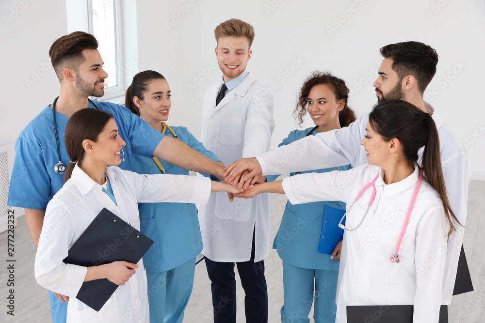 Team of medical workers holding hands together in hospital. Unity concept Team of medical workers holding hands together in hospital. Unity concept