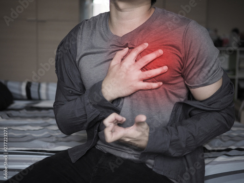 Severe heartache, man suffering from chest pain, having heart attack or painful cramps, pressing on chest with painful expression © Sataporn