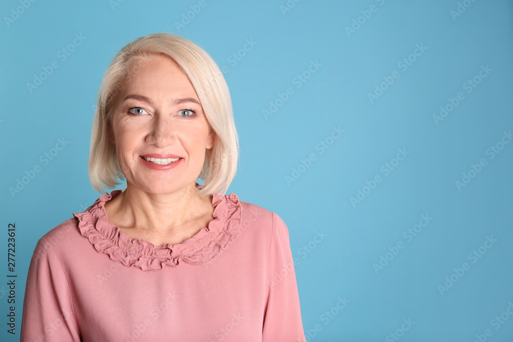 Portrait of charming mature woman with healthy beautiful face skin and natural makeup on blue background, space for text Portrait of charming mature woman with healthy beautiful face skin and natural makeup on blue background, space for text