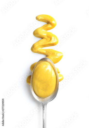 Delicious mustard and spoon on white background, top view. Spicy sauce