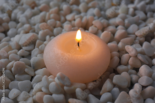 Beautiful burning candle on small white stones