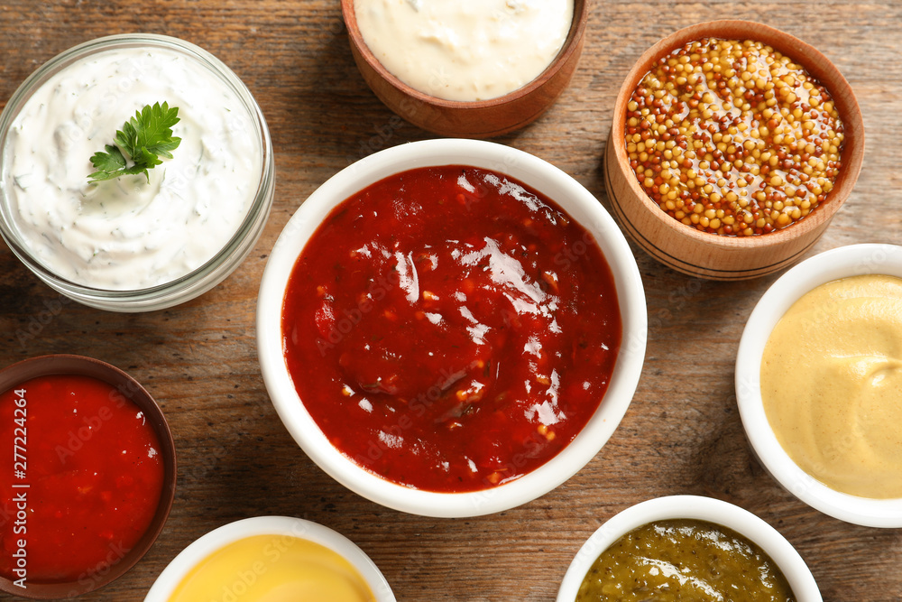 Set of different delicious sauces on wooden table, top view Set of different delicious sauces on wooden table, top view