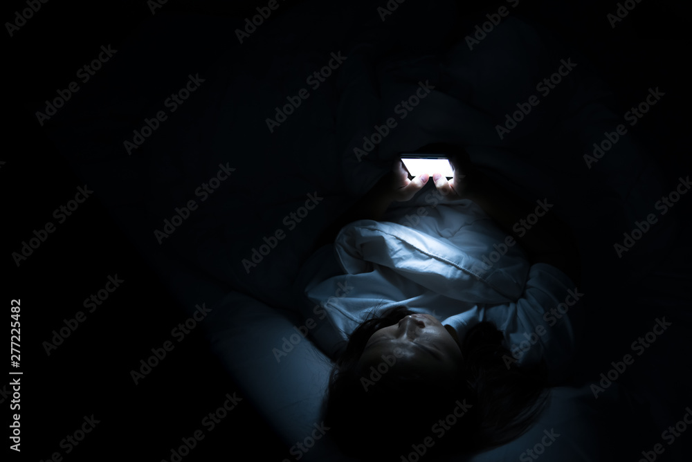 Asian woman play smartphone in the bed at night,Thailand people Asian woman play smartphone in the bed at night,Thailand people
