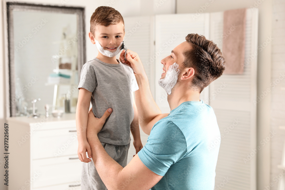 Obraz premium Dad pretending to shave his little son in bathroom