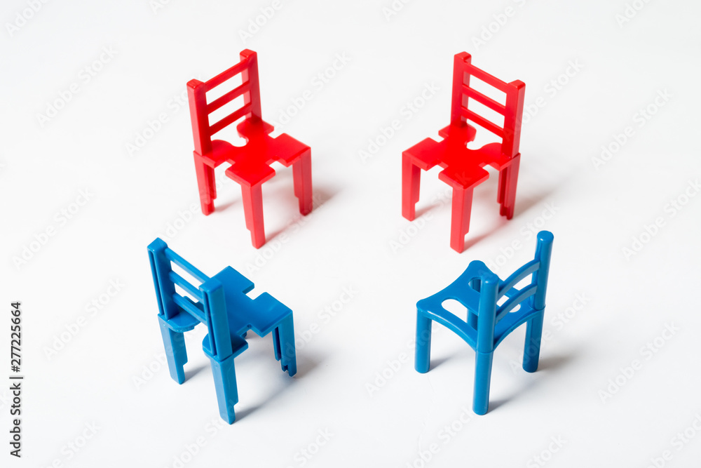 The concept of negotiation, discussion. Several multi-colored toy chairs on white background. The concept of negotiation, discussion. Several multi-colored toy chairs on white background.