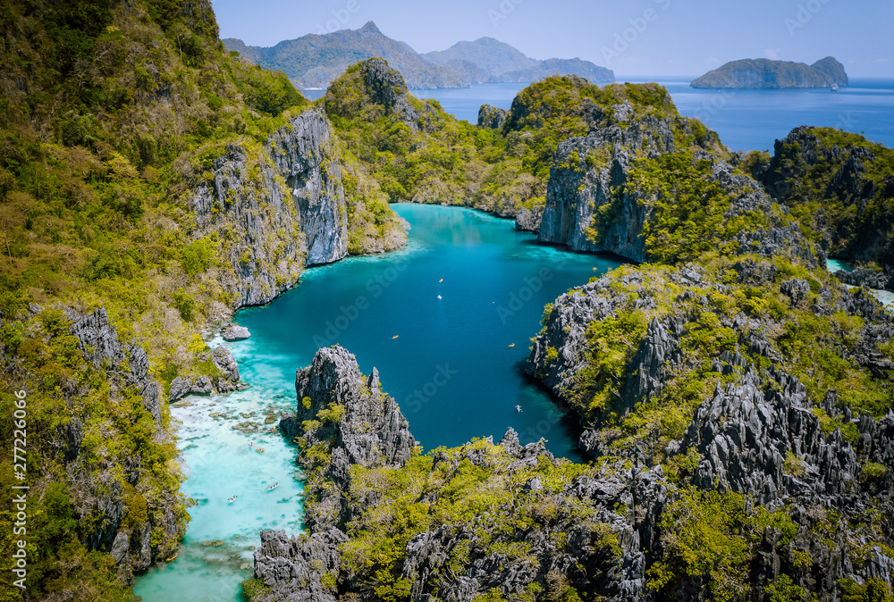 El Nido, Palawan, Philippines. Aerial drone view of beautiful big lagoon surrounded by karst limestone cliffs. Tourists explore area on kayaks
