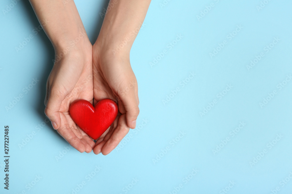 Fototapeta premium Woman holding heart on blue background, top view with space for text. Donation concept
