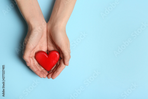 Woman holding heart on blue background, top view with space for text. Donation concept photo