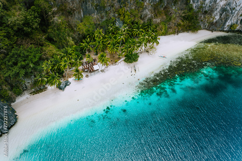 Aerial drone view of abandoned house hut on Pinagbuyutan Island in El Nido. Amazing white sand beach and emerald lagoon water