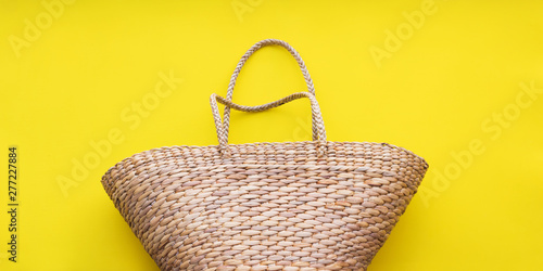 Straw wattled rattan bag yellow background. Woman