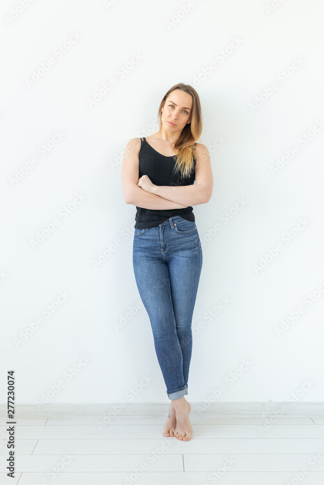 Style, people concept - young woman in jeans and black shirt standing over the white background Style, people concept - young woman in jeans and black shirt standing over the white background