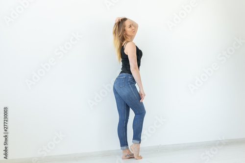 Style, people concept - young woman in jeans and black shirt standing over the white background with copy space