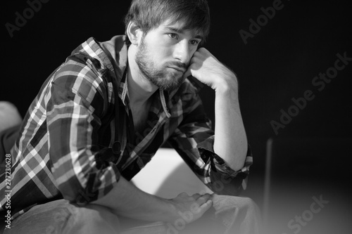 Sad young man sitting on the couch looking into space