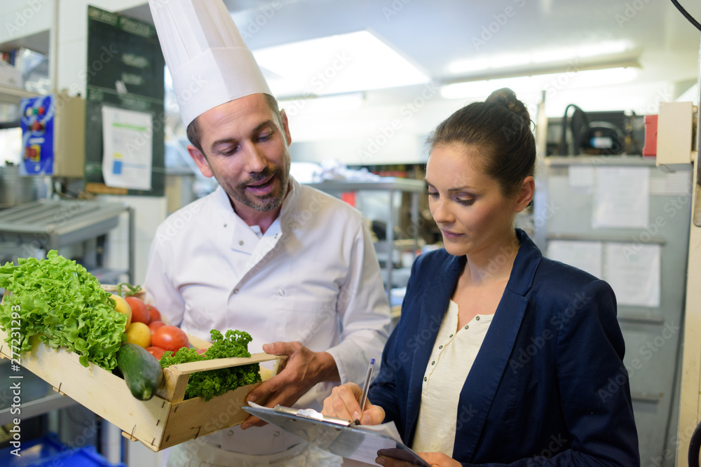 portrait of attractive cook and woman with clipboard in kitchen portrait of attractive cook and woman with clipboard in kitchen