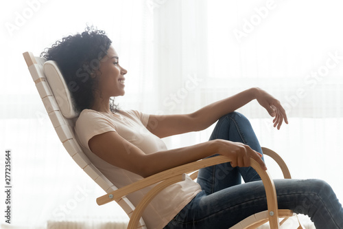 Happy calm african girl resting dreaming sit in rocking chair