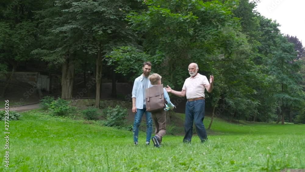 Dad and granddad meets their son from elementary school. joyful child runs into the arms of his parents. Raer view of happy schoolboy runs towards his father and grandfather. the end of the school day Dad and granddad meets their son from elementary school. joyful child runs into the arms of his parents. Raer view of happy schoolboy runs towards his father and grandfather. the end of the school day