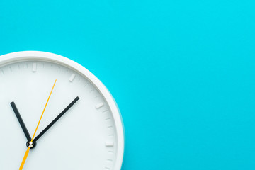 Part of white wall clock with yellow second hand hanging on wall. Close up image of plastic wall clock over turquiose blue background with copy space. Photo of time management or time is going concept