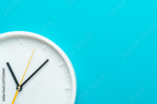 Part of white wall clock with yellow second hand hanging on wall. Close up image of plastic wall clock over turquiose blue background with copy space. Photo of time management or time is going concept photo