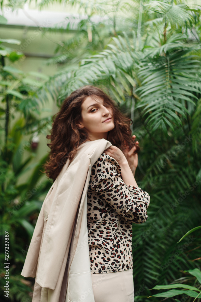 Beautiful pretty girl in a leopard blouse on a background of green jungle Beautiful pretty girl in a leopard blouse on a background of green jungle