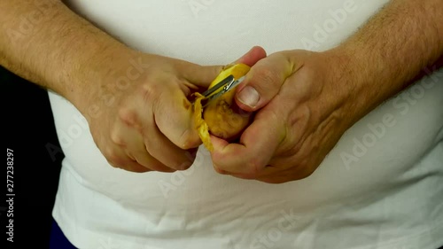 Hands removing skin yellow potato