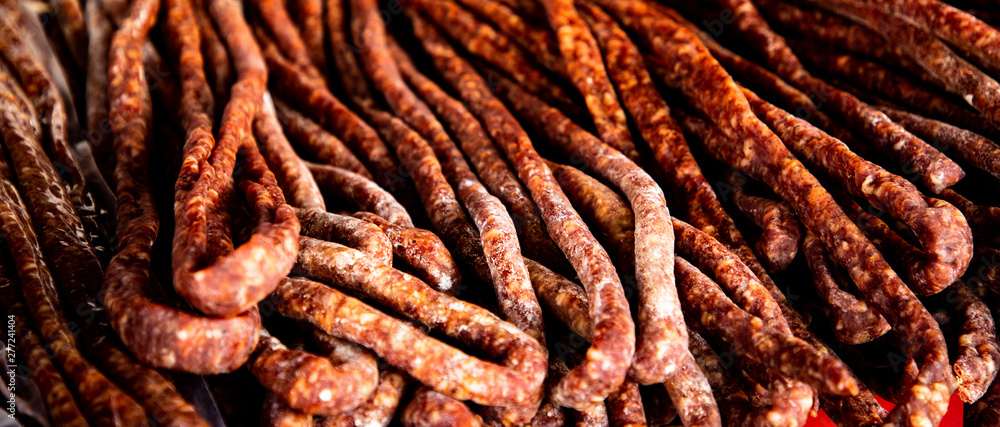 Dry meat salami or sausage on wicker basket Dry meat salami or sausage on wicker basket