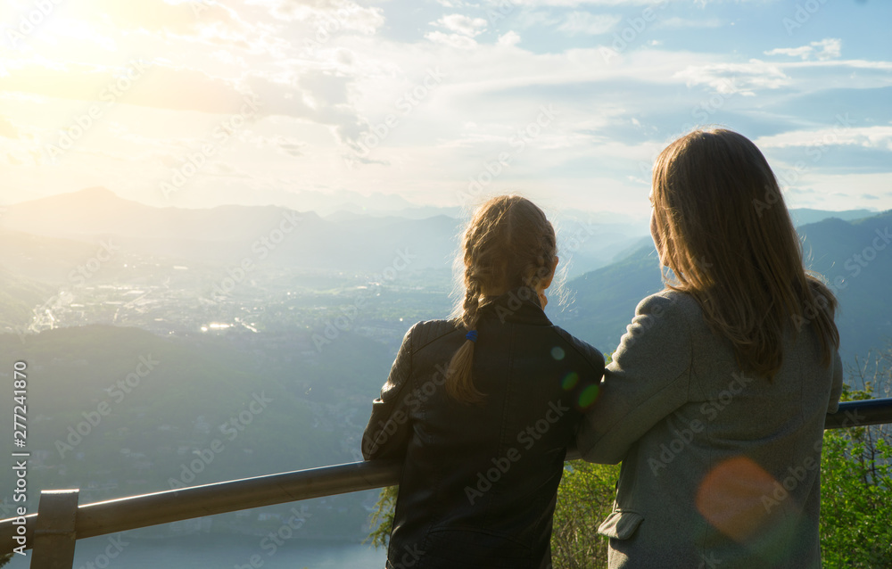 Fototapeta premium Woman and her daughter enjoying sunrise from top of mountain.