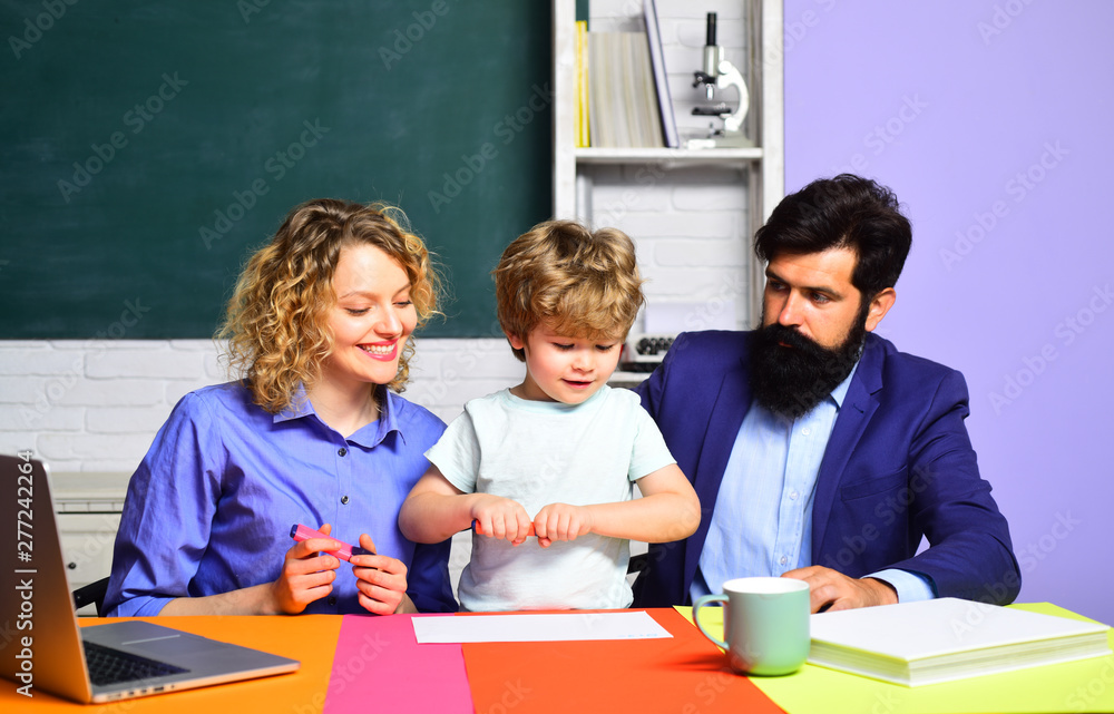 Kid from elementary school with parents in school. Elementary student. Couple helping his son to make homework. First day at school. Little schoolboy ready to study. Parenting education. September 1.