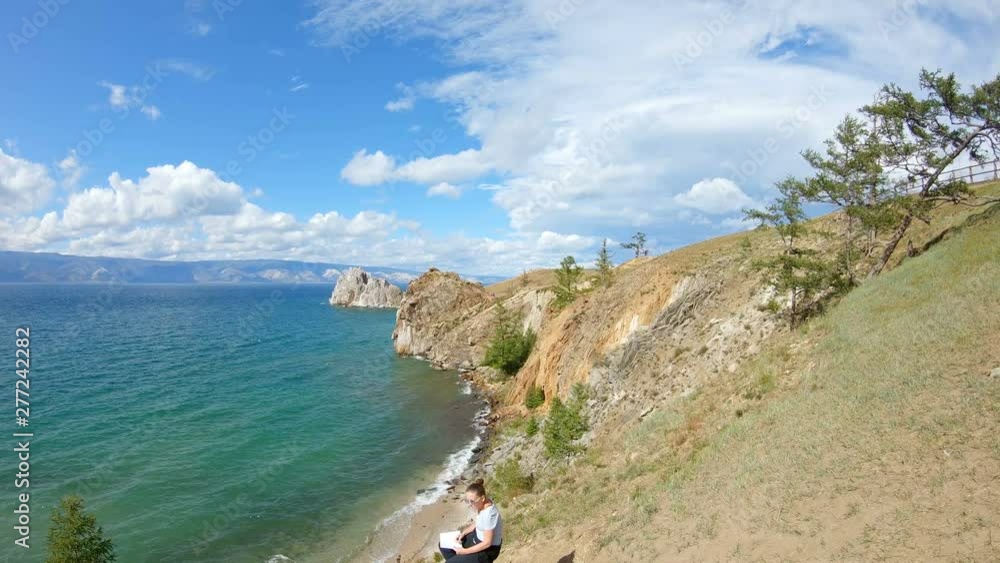 Aerial view of a girl sitting on a steep bank and drawing. Beautiful landscape. Slow motion, 4K Aerial view of a girl sitting on a steep bank and drawing. Beautiful landscape. Slow motion, 4K