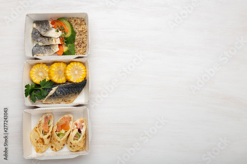 Three kinds of lunch boxes with fish and vegetables lie on a white table. Copy space. Healthy eating concept