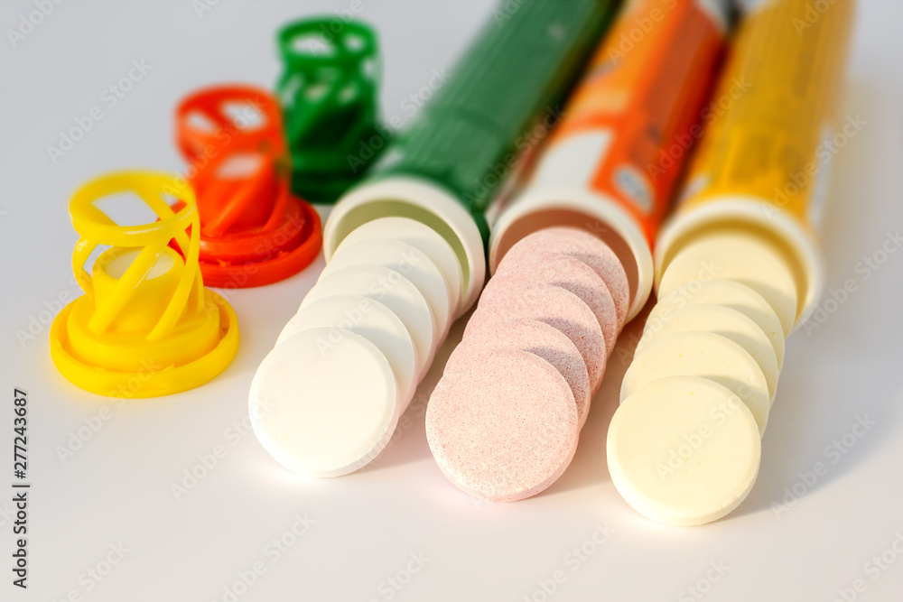 Three kinds of soluble effervescent vitamins spilled out of their plastic bottles on a white background. Under a sunlight. Vitamins and nutritional supplements. Health care and medical. Three kinds of soluble effervescent vitamins spilled out of their plastic bottles on a white background. Under a sunlight. Vitamins and nutritional supplements. Health care and medical.