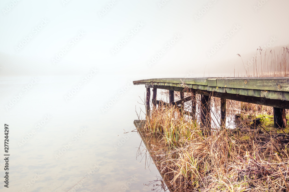 Misty lake in the middle of the forest and old wooden bridge