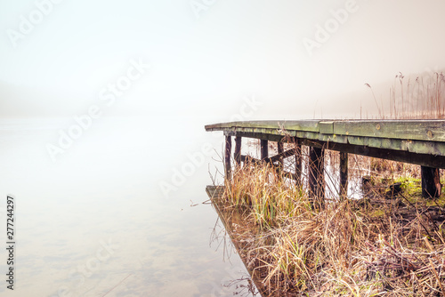 Misty lake in the middle of the forest and old wooden bridge