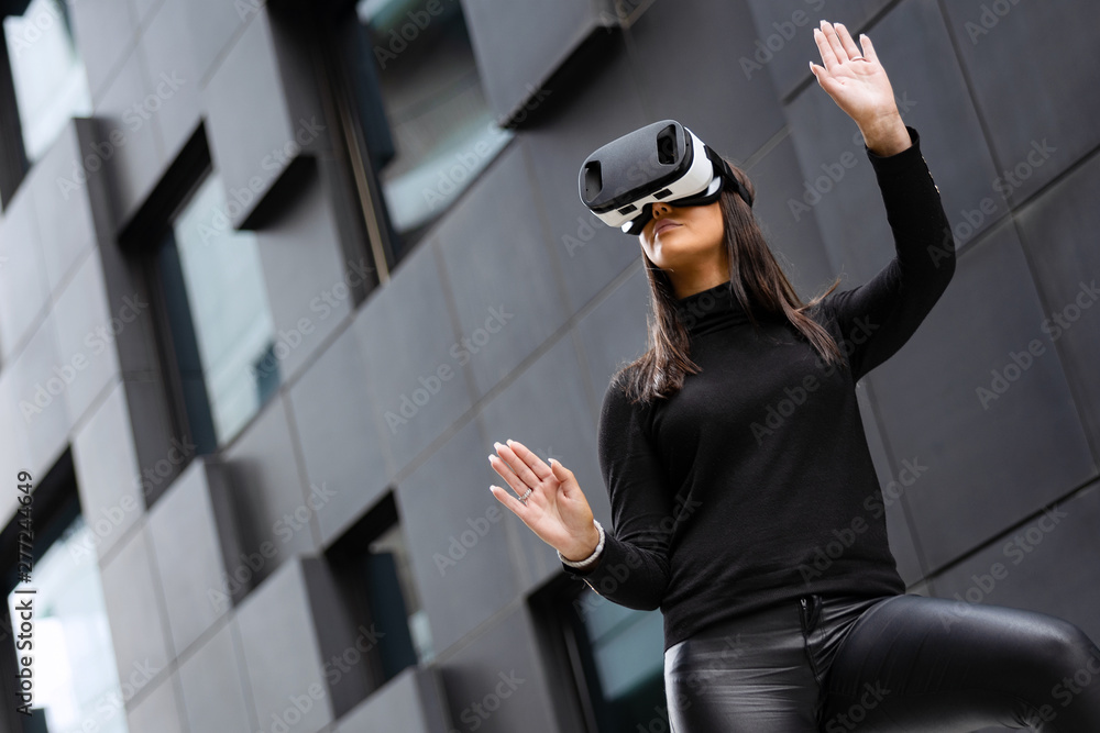 Woman Wearing Virtual Reality Technology Glasses Against Futuristic Building Woman Wearing Virtual Reality Technology Glasses Against Futuristic Building