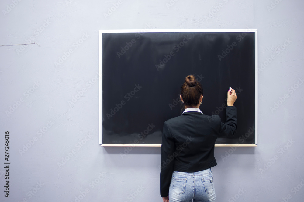The teacher is standing at the blackboard close-up The teacher is standing at the blackboard close-up