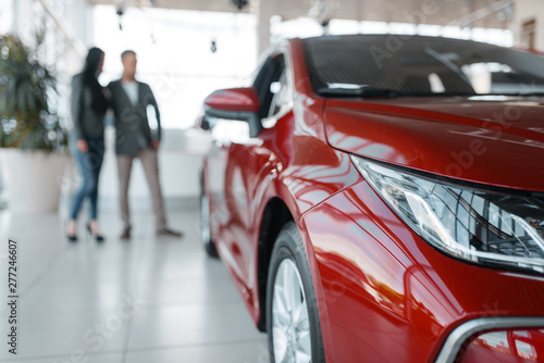 Couple buying new red car in showroom photo