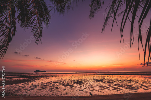 Beautiful Silhouette coconut palm tree on the tropical beach. Bright colorful sunset sky over the ocean water, Thailand.