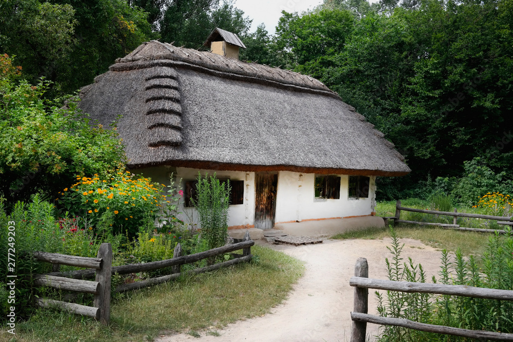 Old Ukrainian house. Ukrainian hut of the nineteenth century. Summer landscape, flowers in front of the house, sunlight. Village Pirogovo. Old Ukrainian house. Ukrainian hut of the nineteenth century. Summer landscape, flowers in front of the house, sunlight. Village Pirogovo.